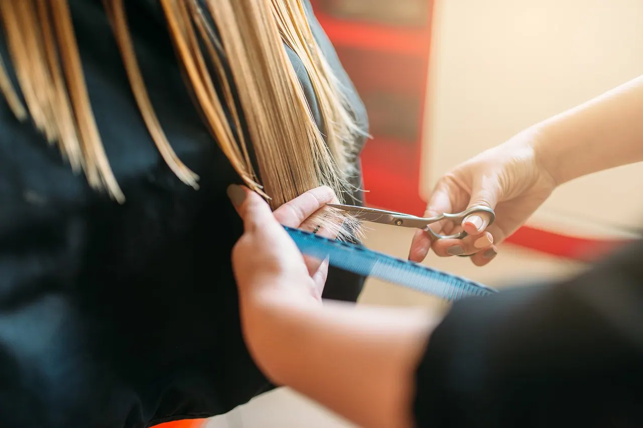 Parrucchiera che taglia i capelli con le forbici