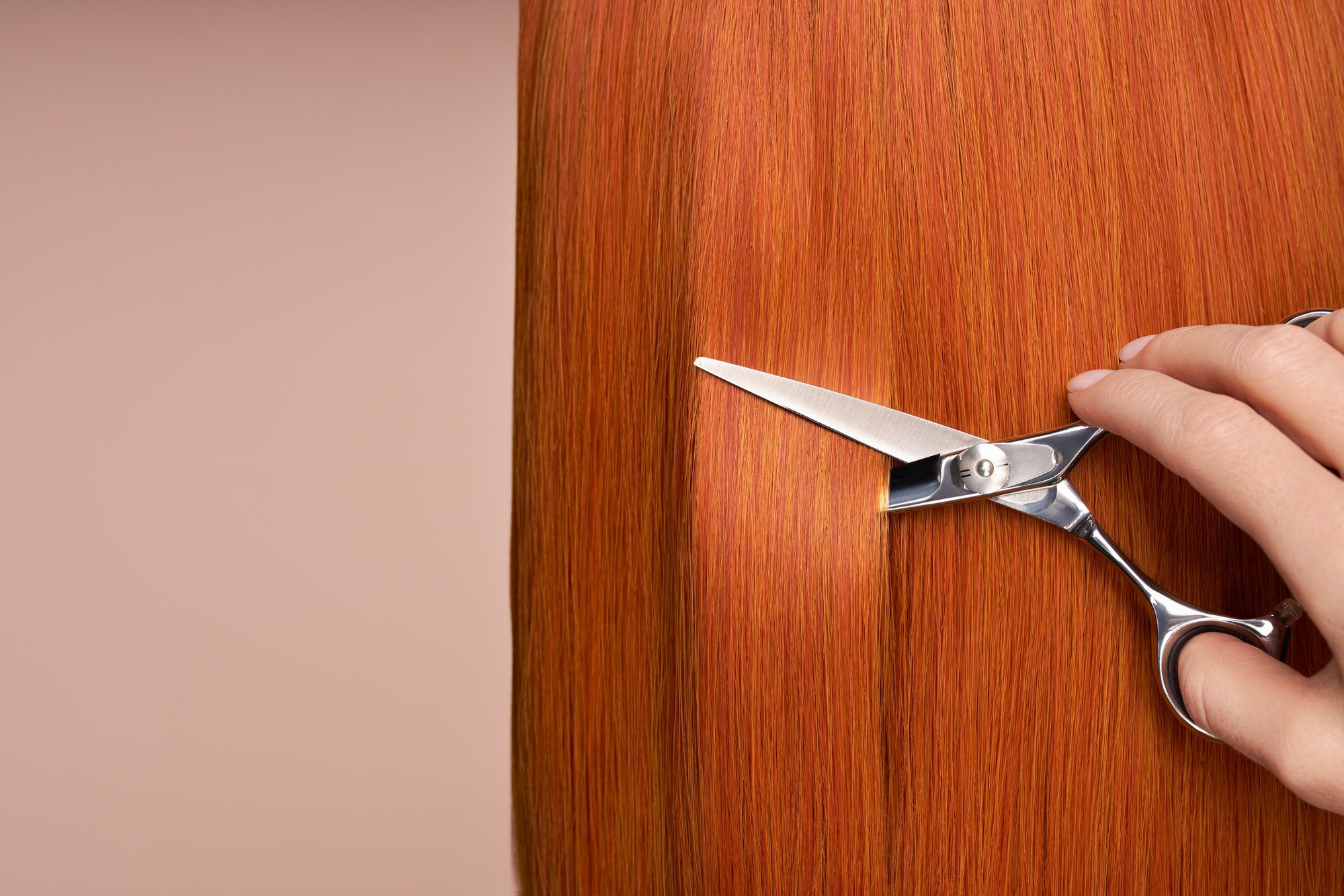 hairdresser cuts long red hair with scissors